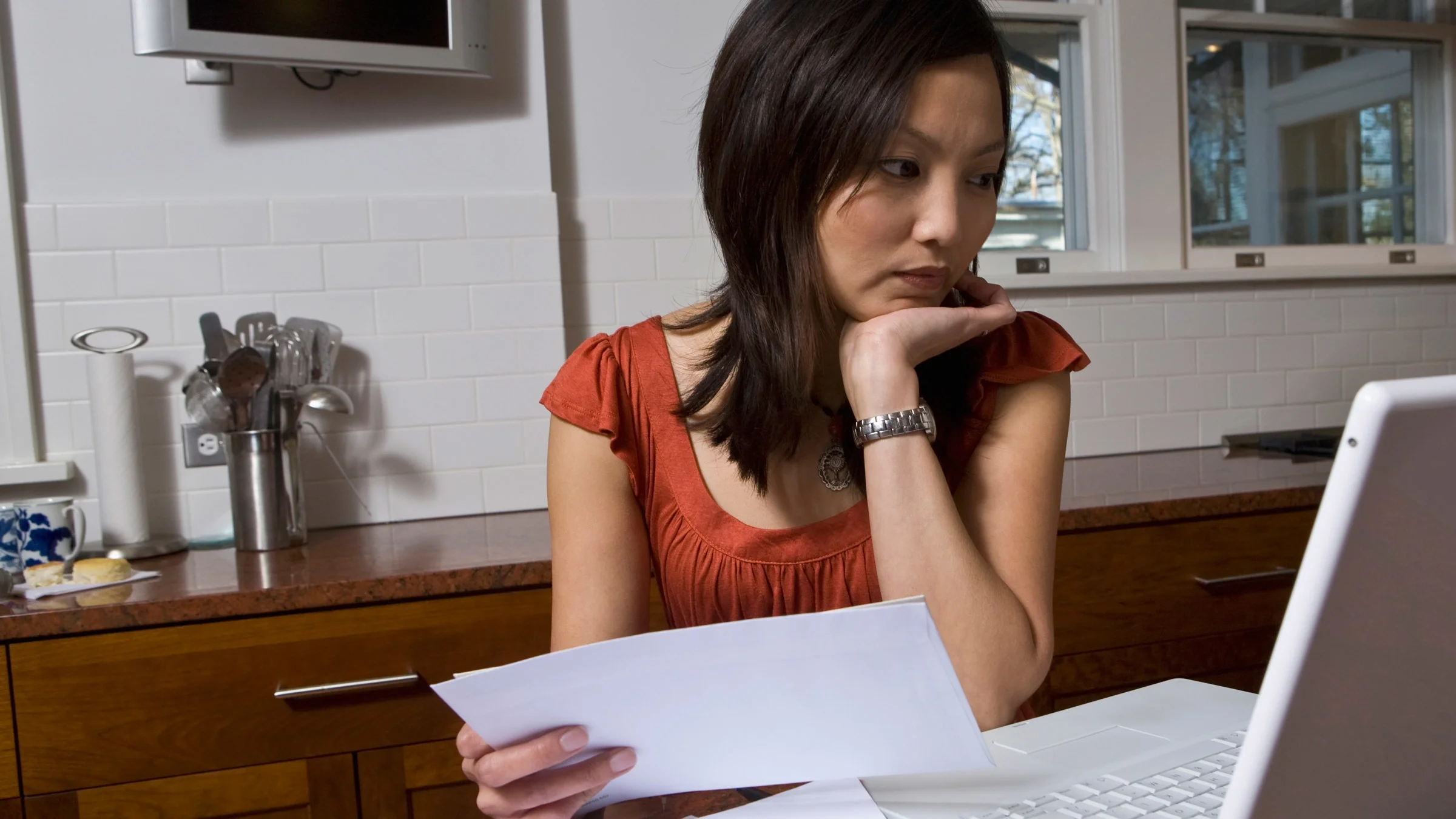 A person thinking while paying bills on their laptop.