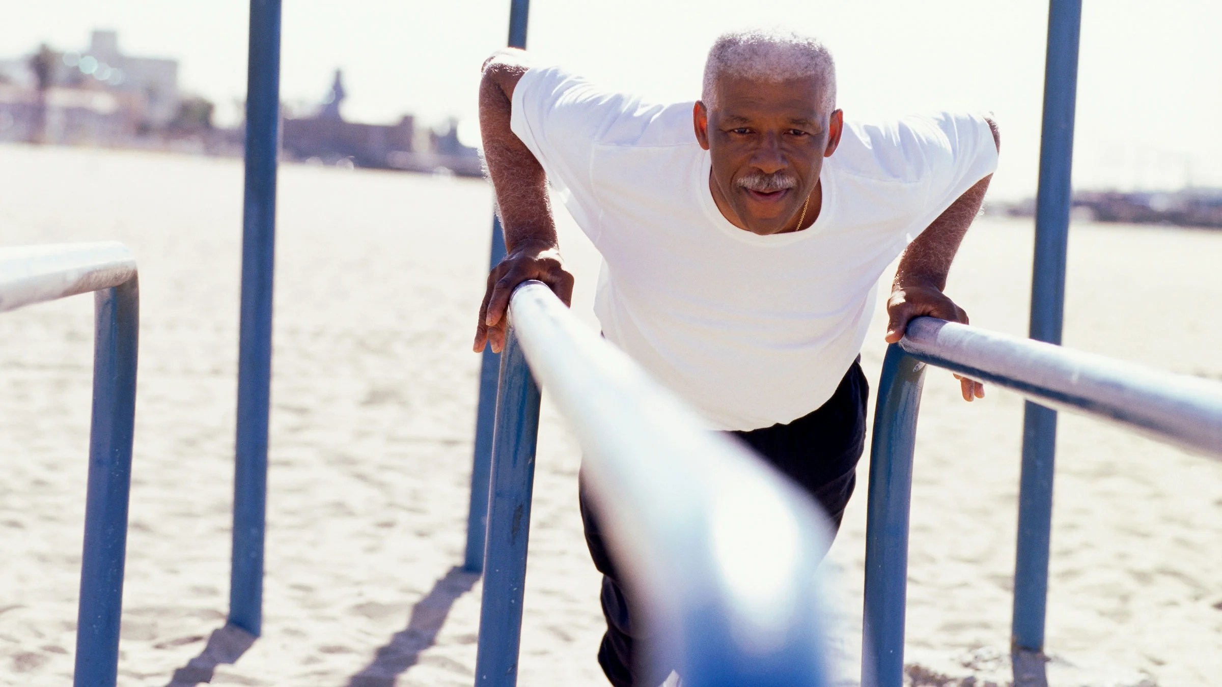 Older man living an active lifestyle and standing at parallel bars