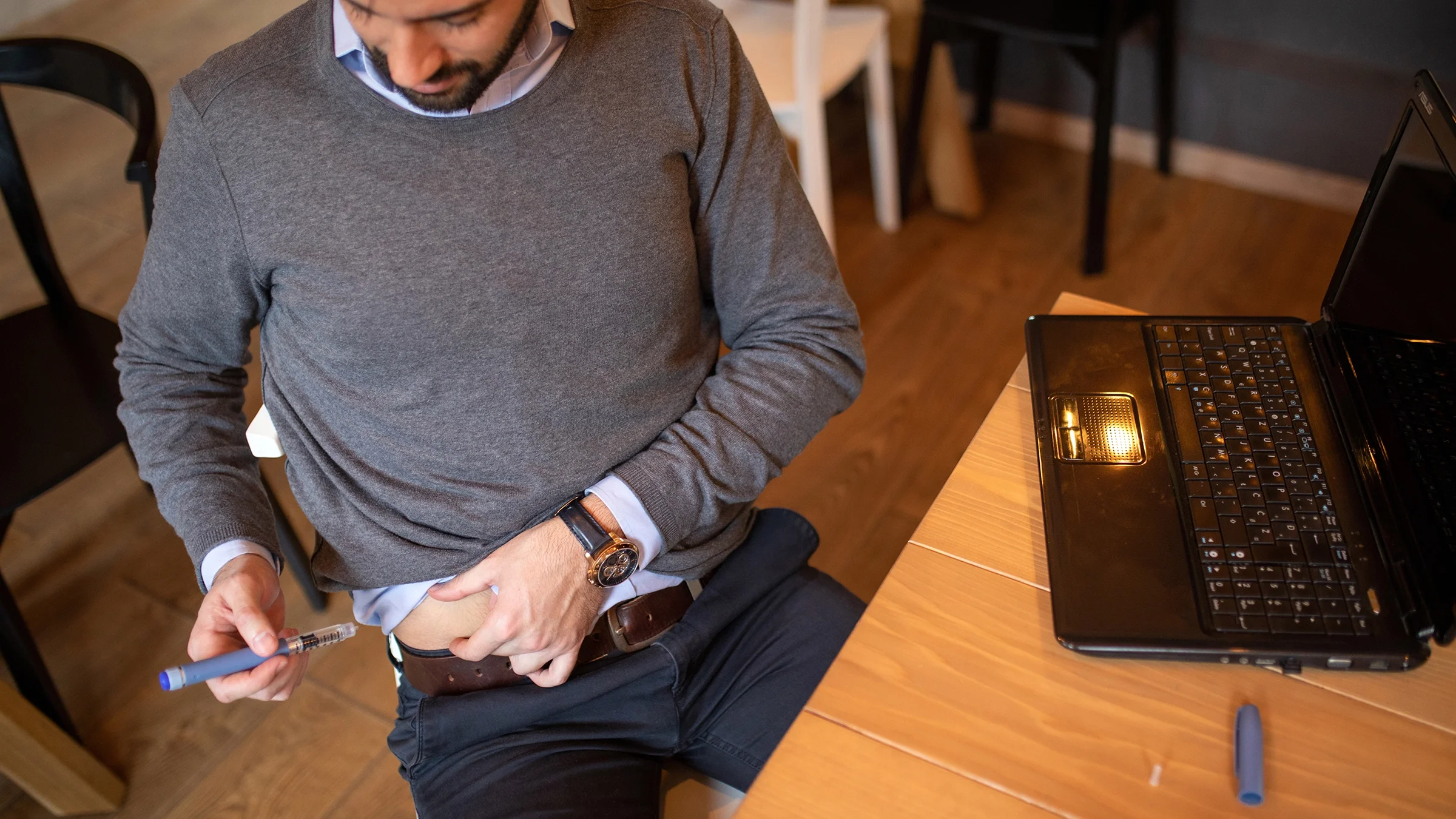 A man is taking an insulin shot while at work.