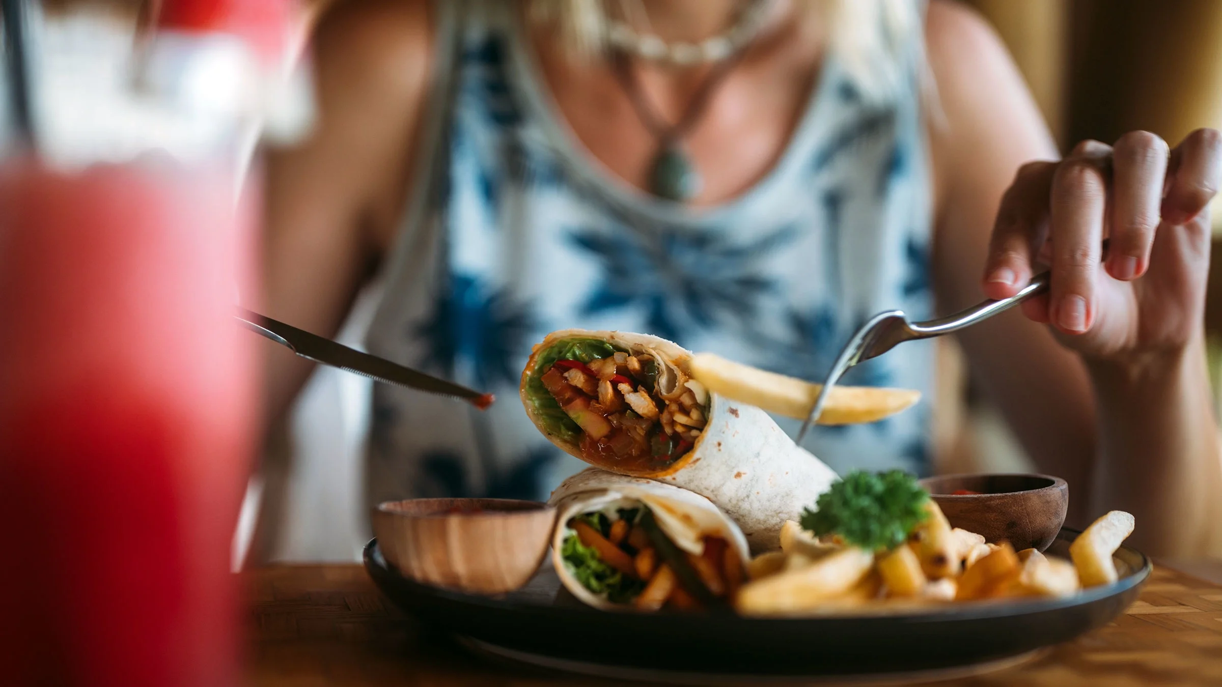 A woman eats a wrap and french fries.