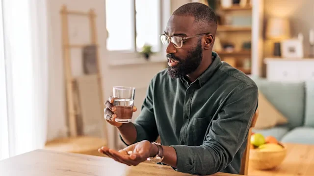 minoxidil: man taking pill with water 2218000694