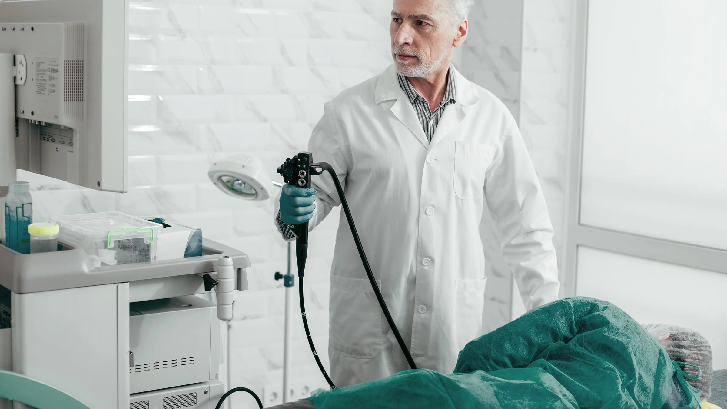 Doctor performing an endoscopy on a patient lying down.
