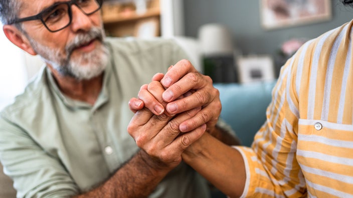 A man holds a woman’s hand, showing empathy and support.