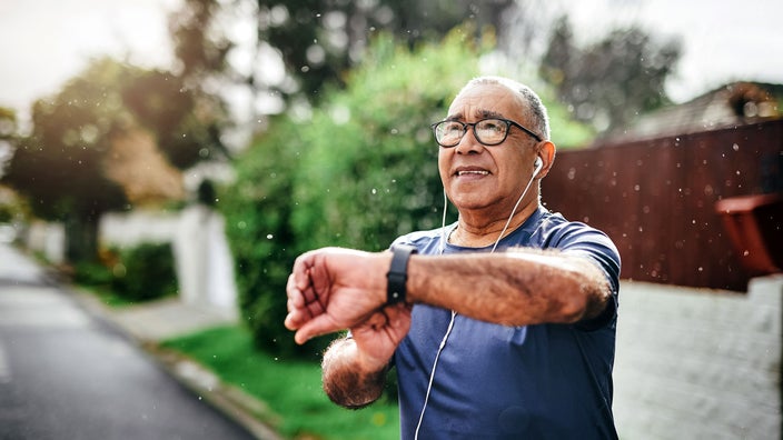 An older man is checking his watch after going for a walk outside.