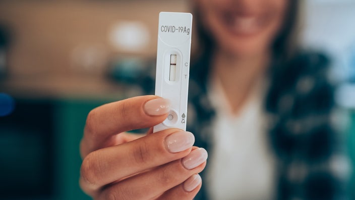 Close-up of happy woman holding negative COVID-19 result strip