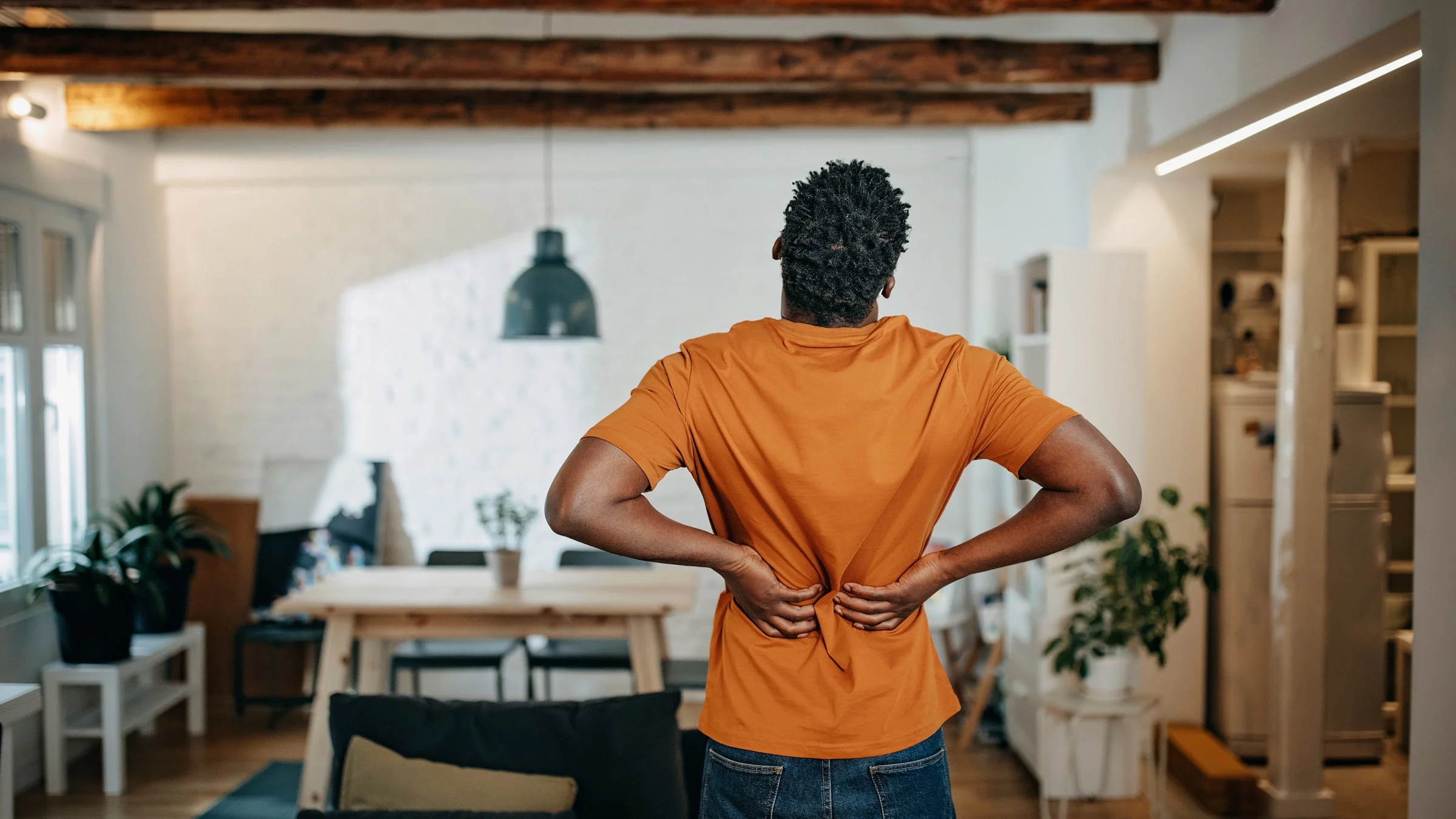 A young man holding his back in pain.