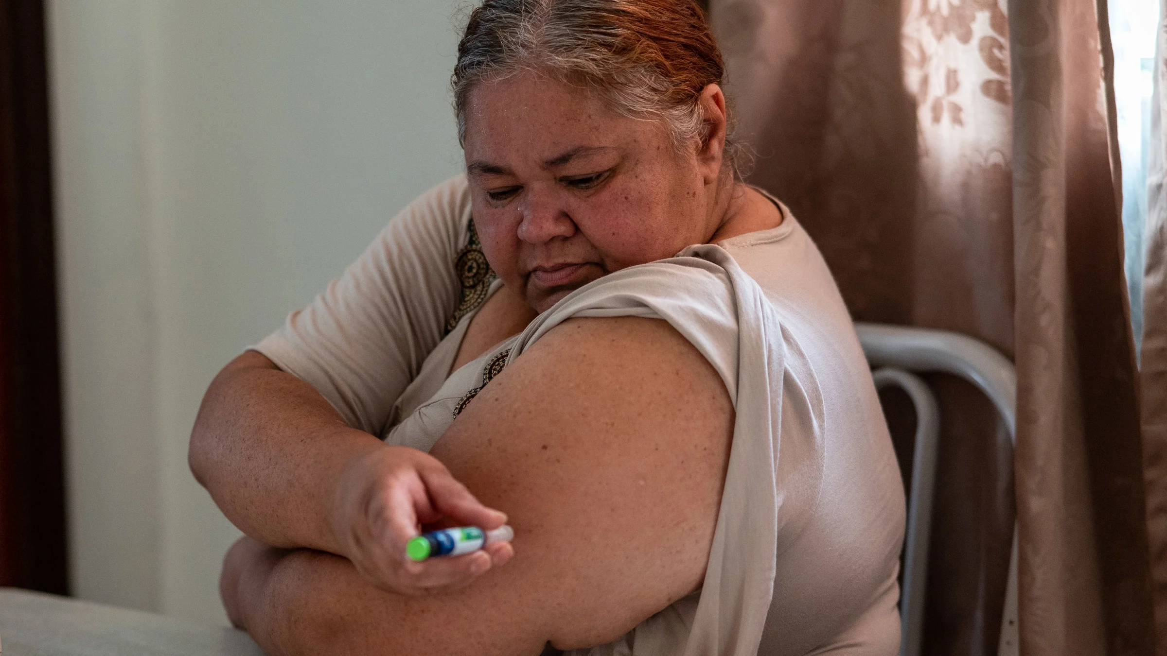 A person self-injecting a weight loss medication into their upper arm.
