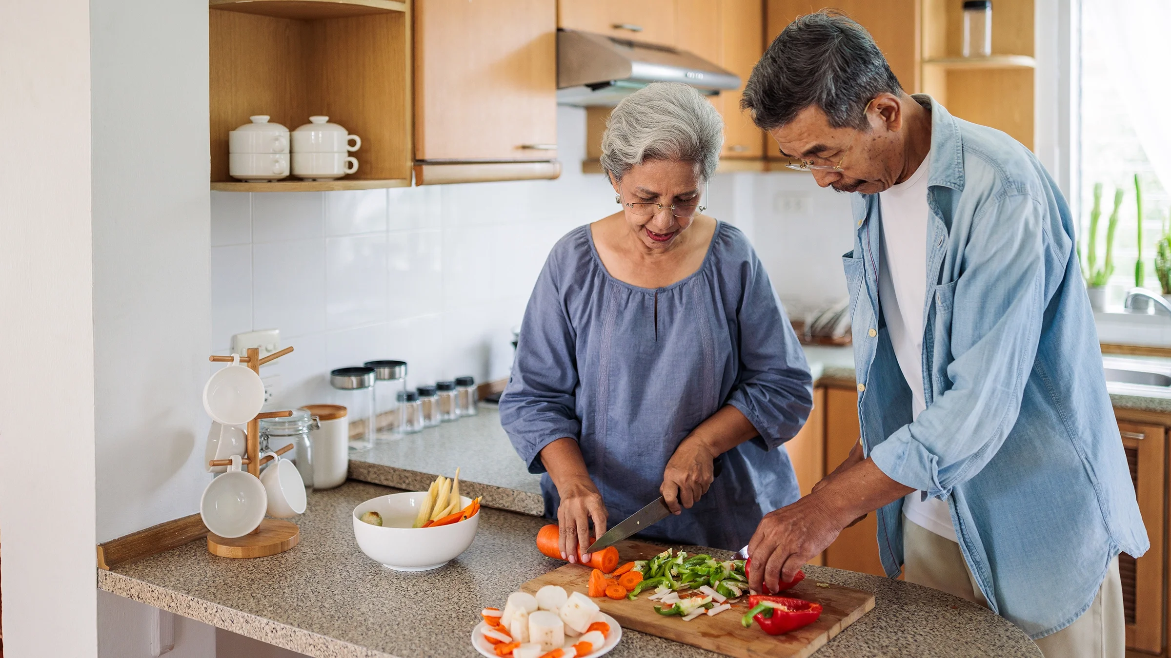 Older couple prepare a nutritious meal in a home kitchen.