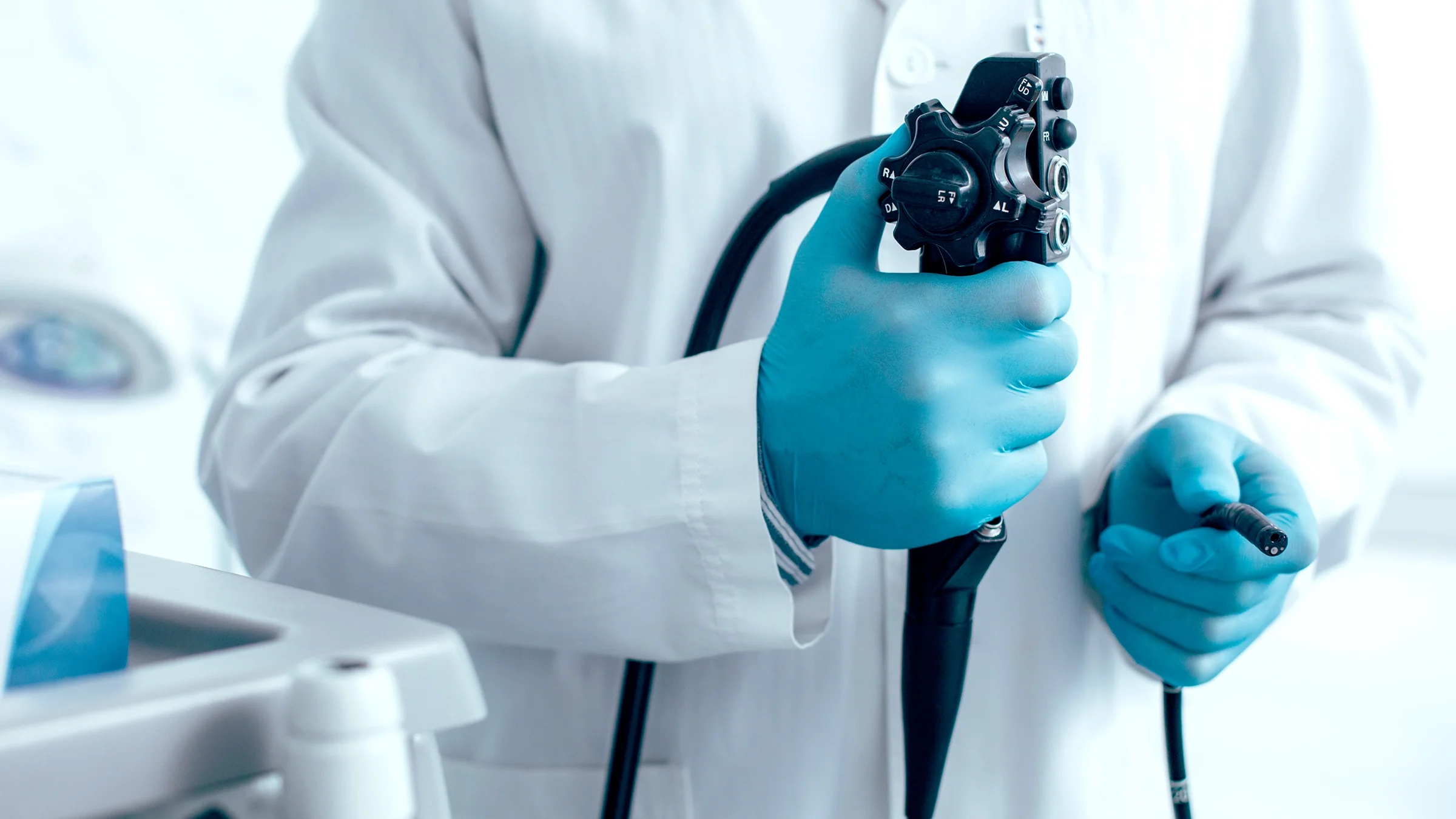 Cropped close-up of a doctor in blue medical gloves holding an endoscope.