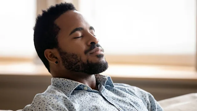 Health: Mental health: man taking deep breathe on couch-1203044203