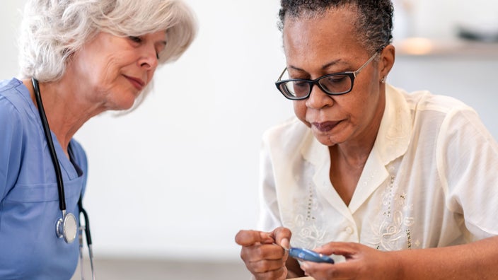 Medical professional helping patient self-test for diabetes