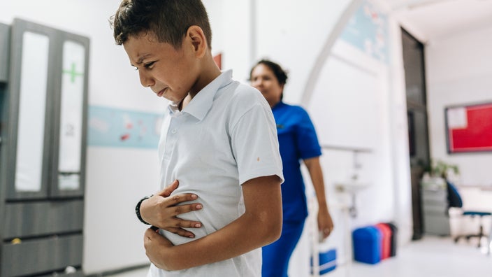 A child with appendicitis is holding his belly as he experiences pain.