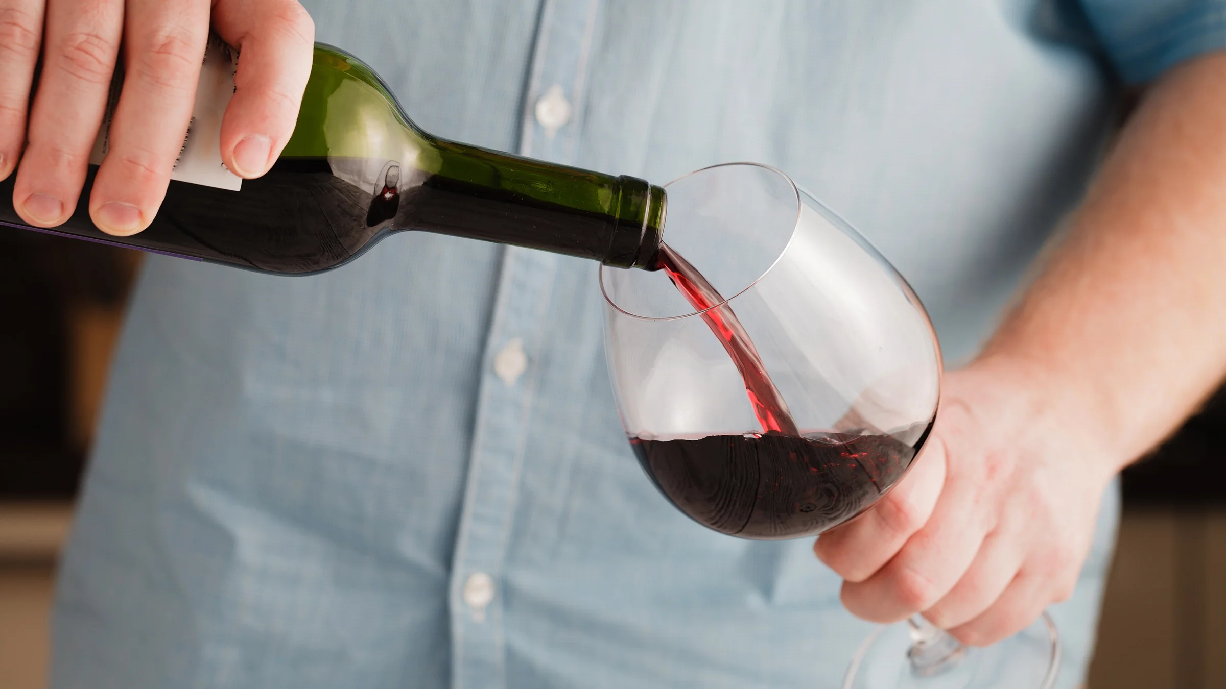 A man pours a glass of red wine.