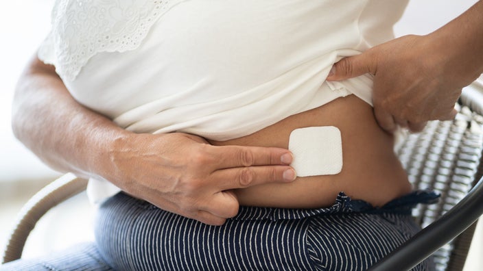 Cropped shot of a woman putting a hormone patch on her abdomen.