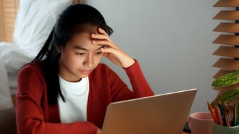 Health: Digestive: young woman stressed at her laptop-1312894444