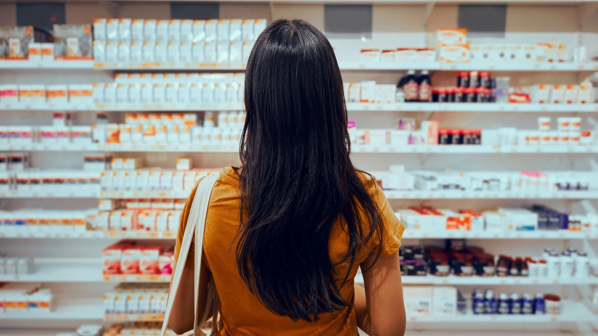 Rear view of someone checking pharmacy shelves. 