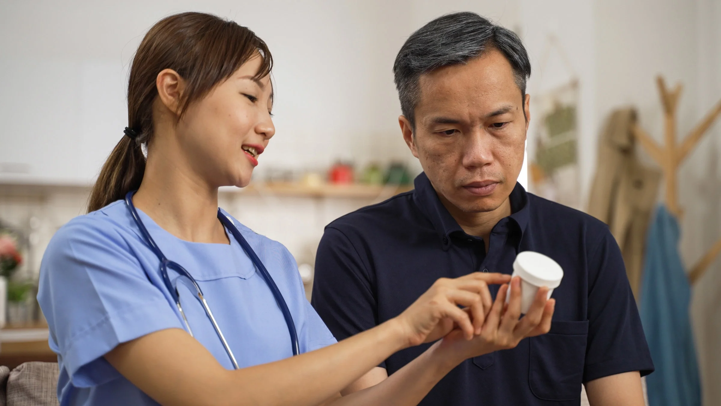 A nurse explaining a pill bottle to man.
