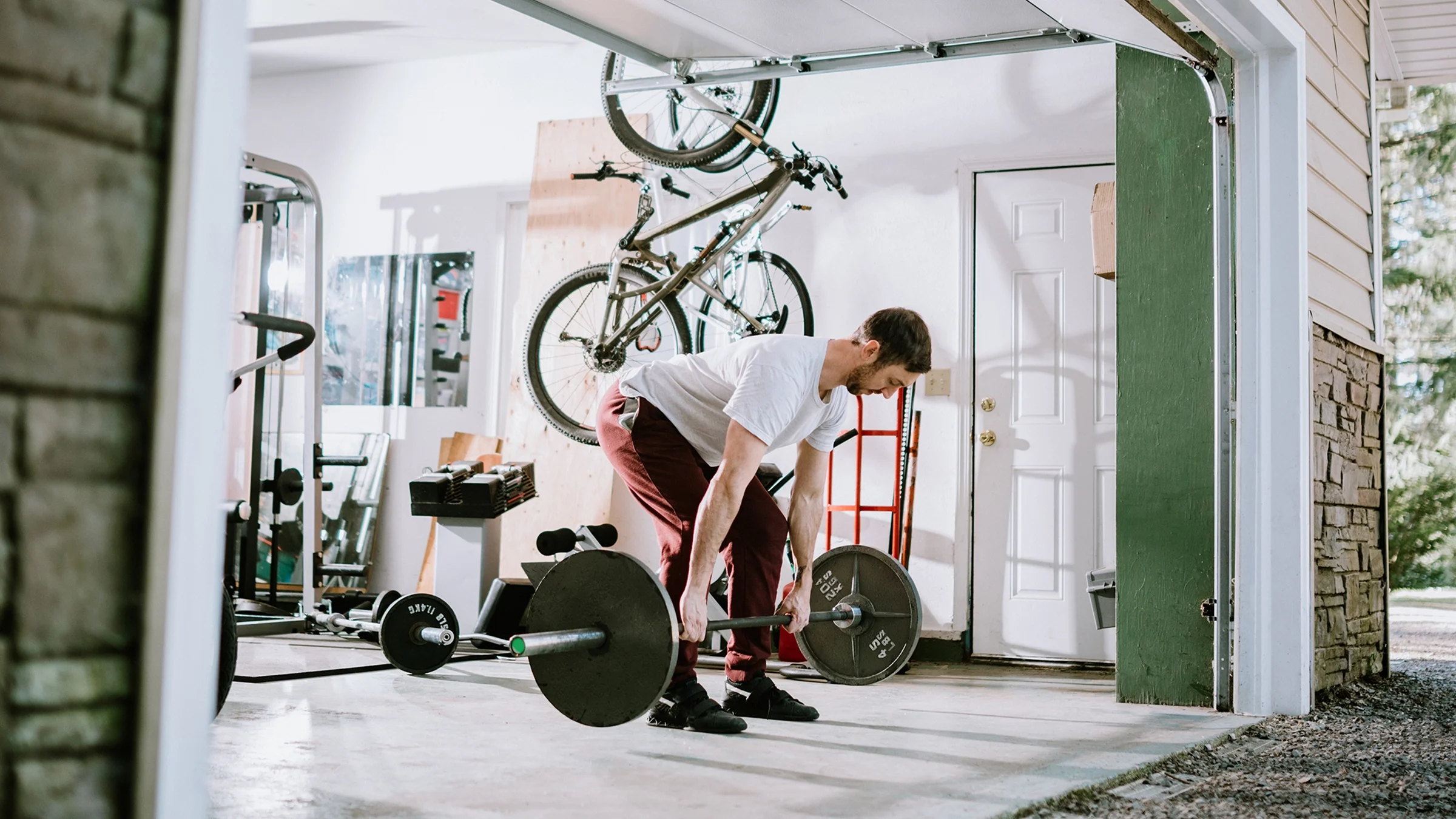 Man doing deadlift exercise in his at-home gym in the garage.