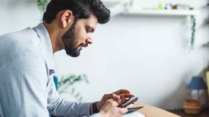 A man uses a mobile phone at home.