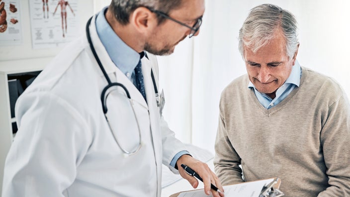 A doctor discusses non-Hodgkin lymphoma with an older adult in his office.