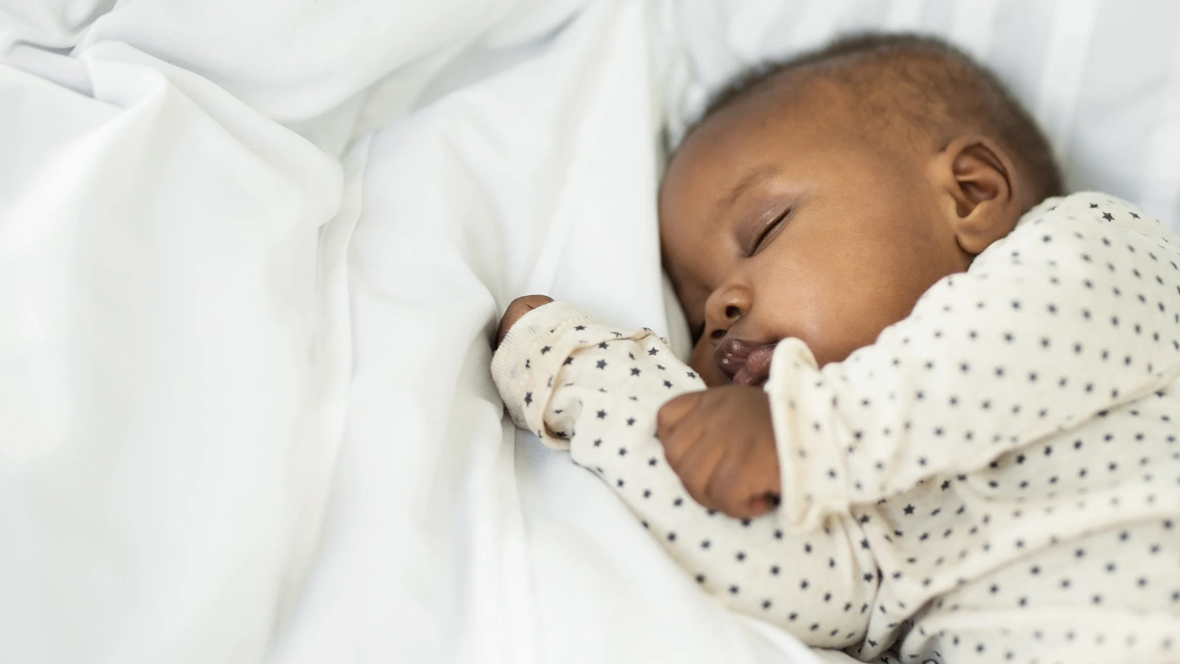 Portrait of a newborn baby laying on white sheets.