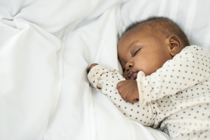 Portrait of a newborn baby laying on white sheets.