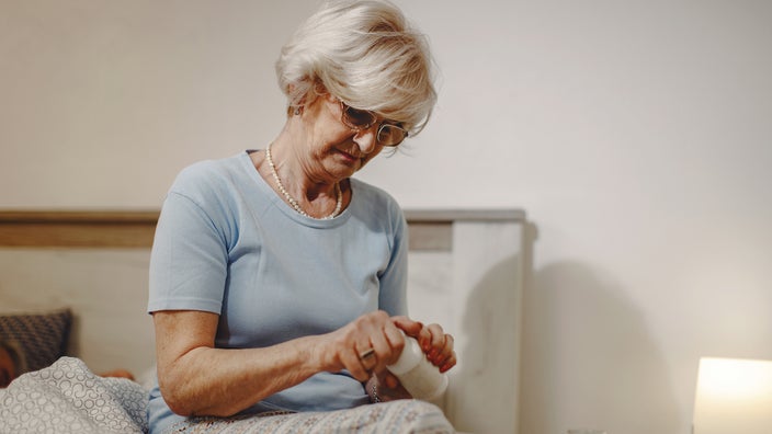 A woman removes the cap off her pill bottle in order to take her medication.