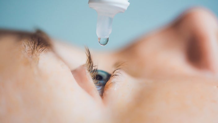 Closeup of a person using an eyedropper to put drops into their open eye.