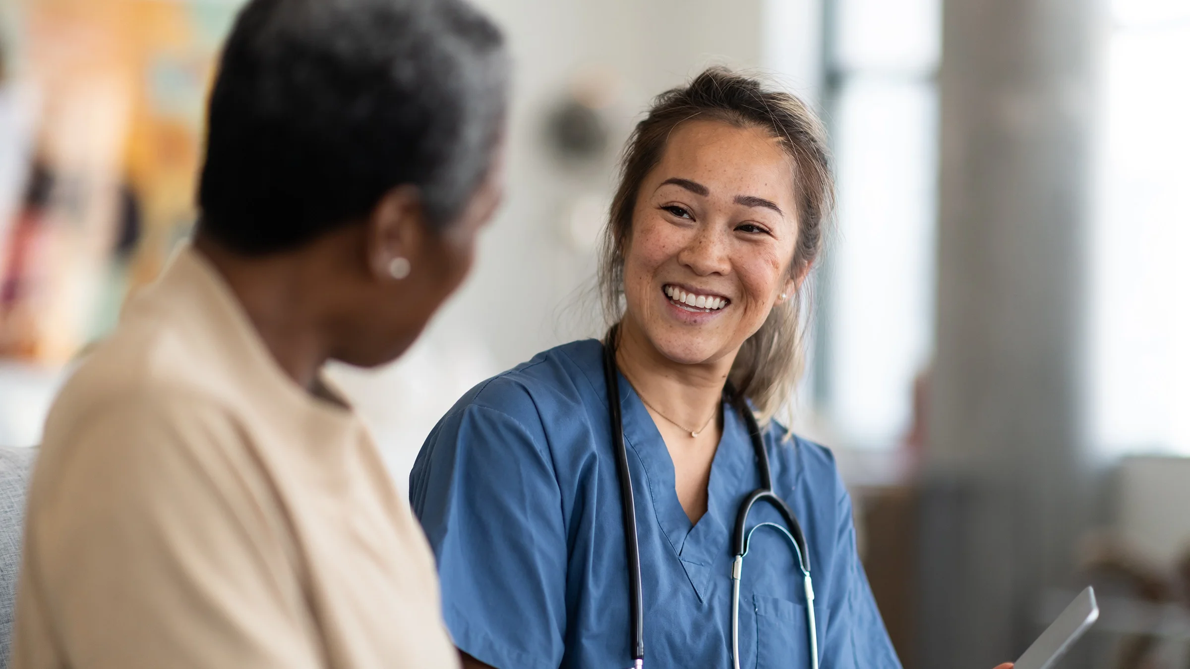 Smiling nurse talking with a client next to her.