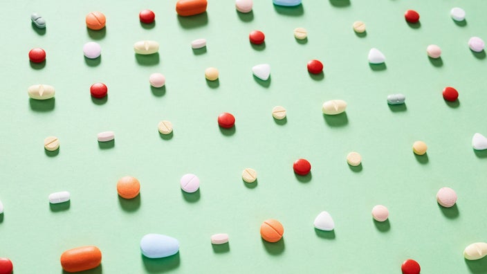 Rows of various pills on a light green background. They are lined up on a slight diagonal with the perspective shifted so it looks like the pills are fading off into the distance.
