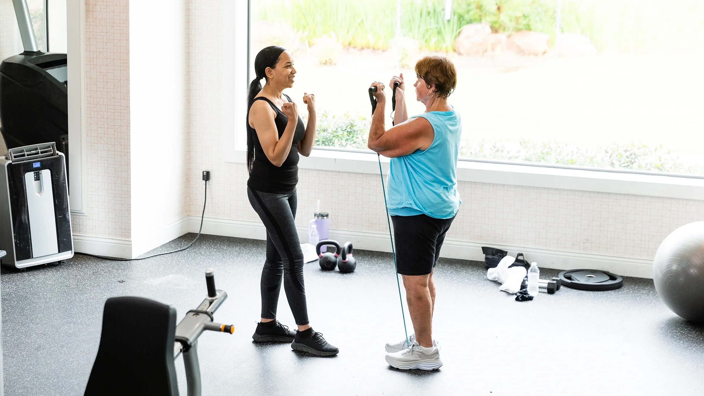 Woman using resistance bands for a workout with personal trainer.