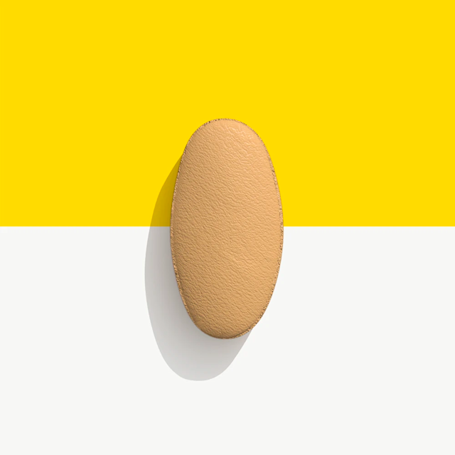 Beige, oval-shaped pill on a yellow and white background.