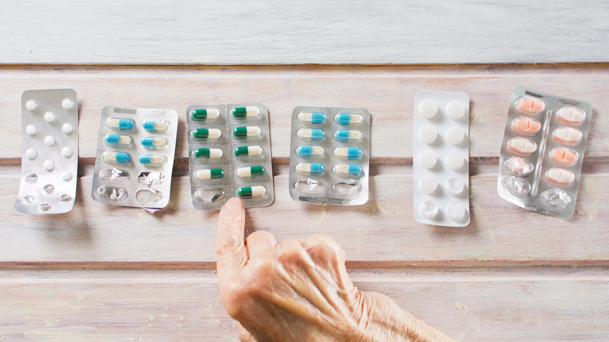 A hand pointing at a blister pack from a row of blister packs.