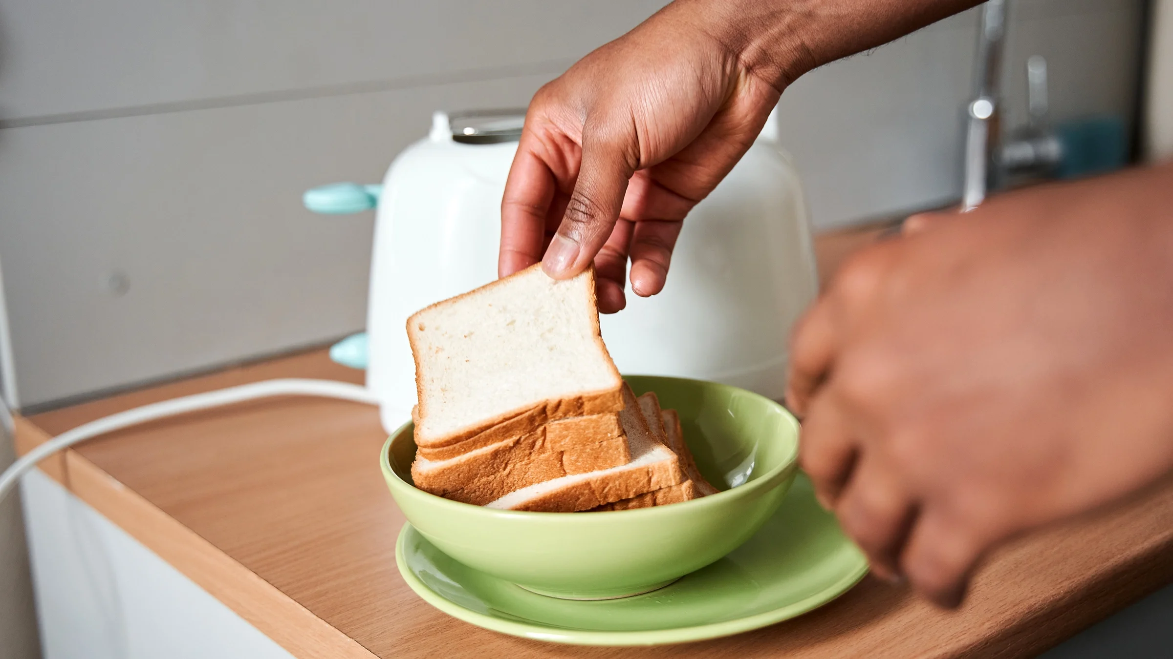 Close-up of a man grabbing a slice of bread from a bowl.