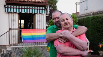 LGBTQ: older gay couple hugging outside home 1414830142