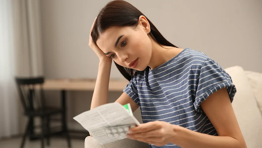 Young woman with straight hair reading a medication pamphlet on side effects of the drug she is taking.
Liudmila Chernetska/iStock via Getty Images
