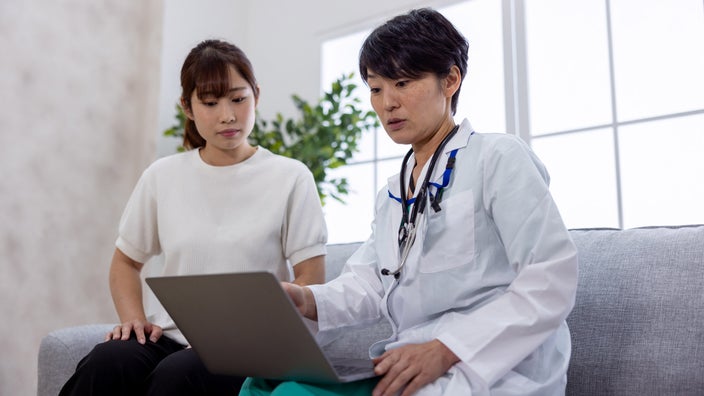 A female patient and doctor looking at a laptop on a couch.