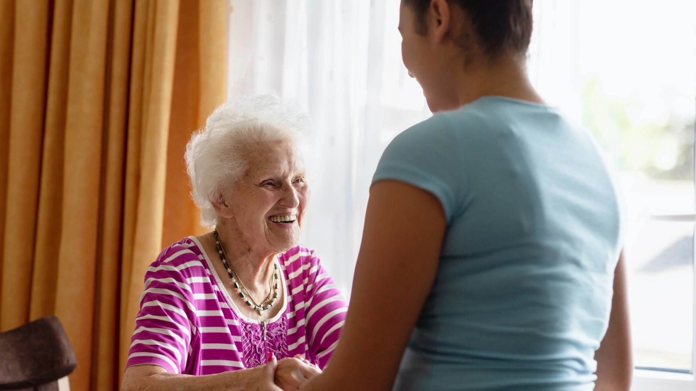 A caretaker helping a senior resident stand.