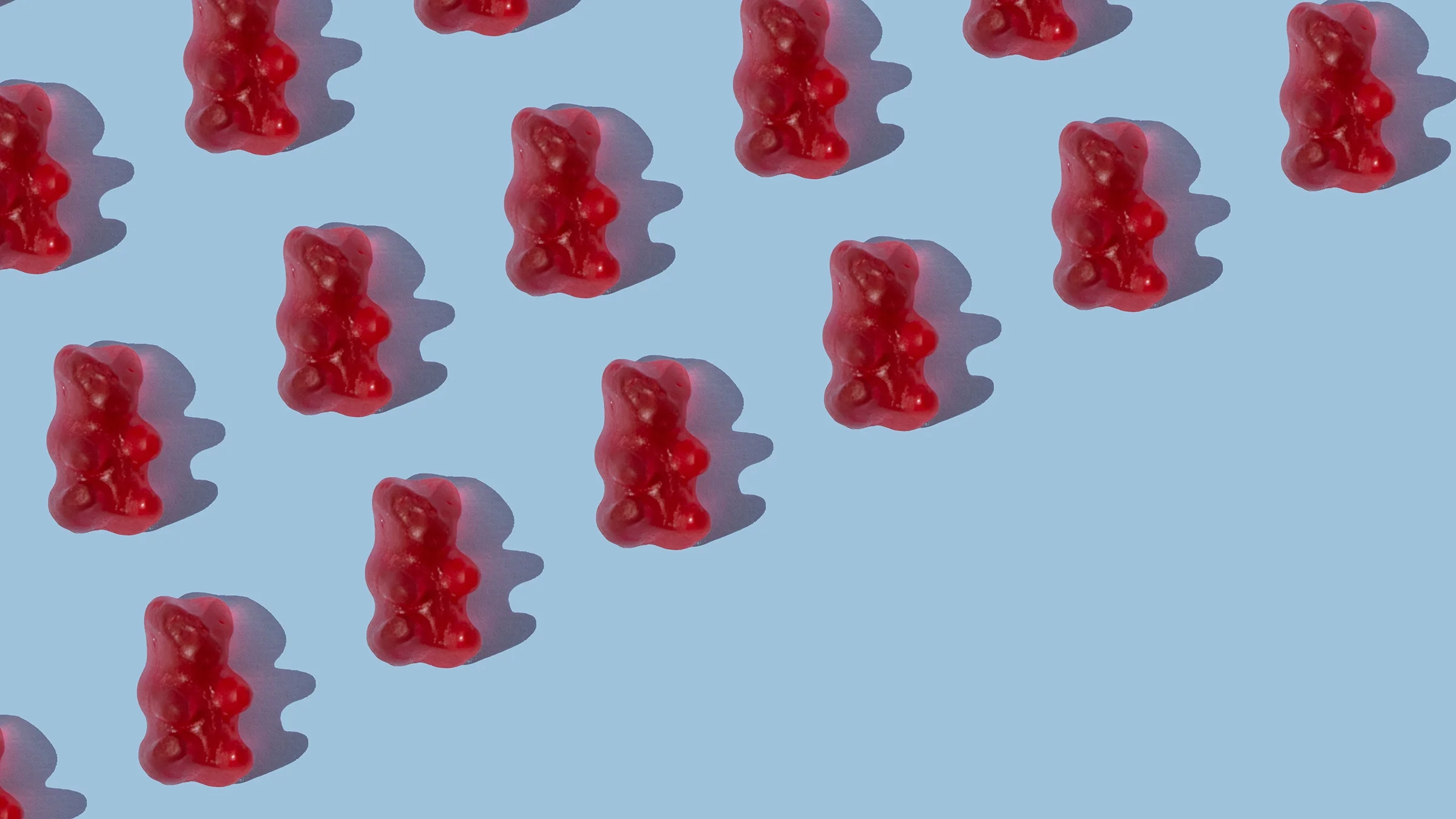 Red gummy bears creating a diagonal pattern on a blue background.