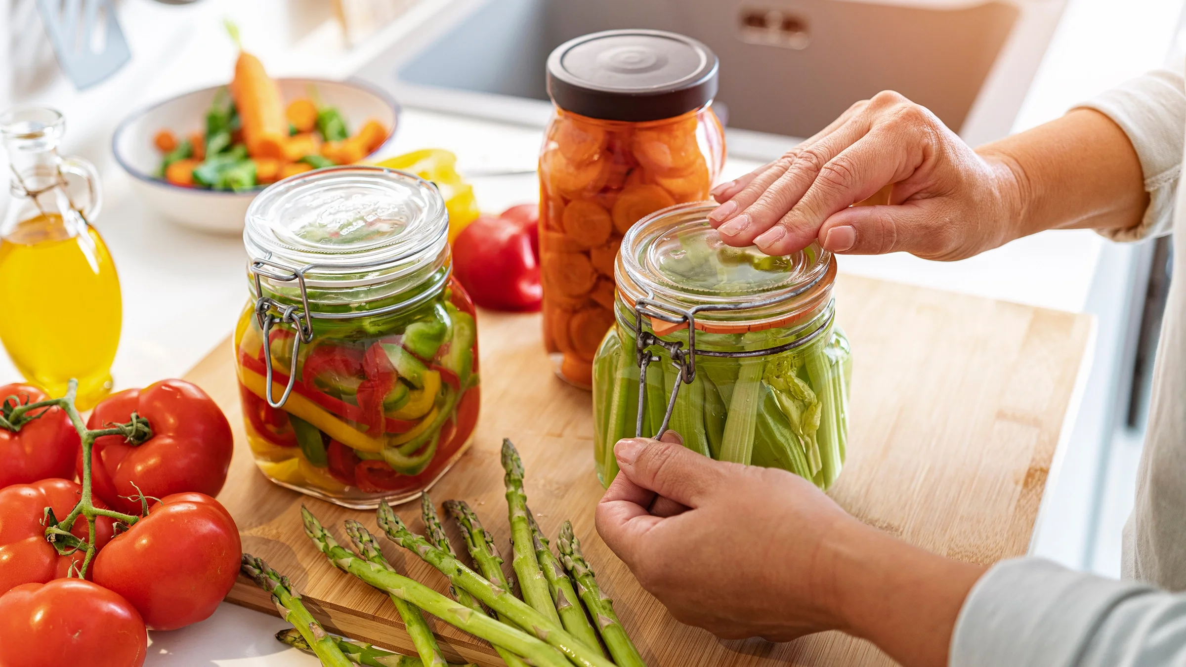 A woman opens a jar of pickled vegetables.