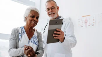 Health: Xarelto: doctor using digital tablet with patient 1585065585