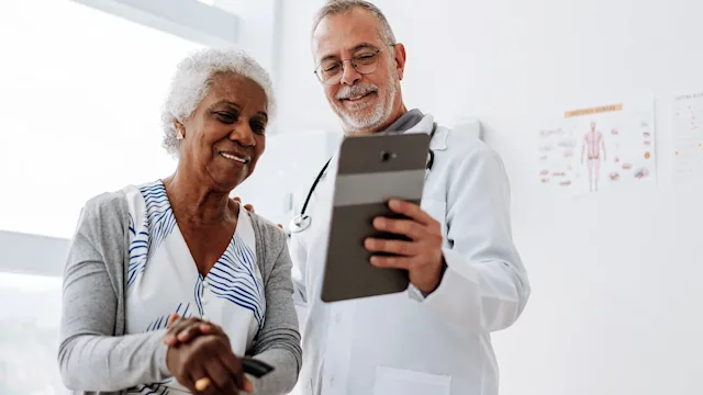 Health: Xarelto: doctor using digital tablet with patient 1585065585