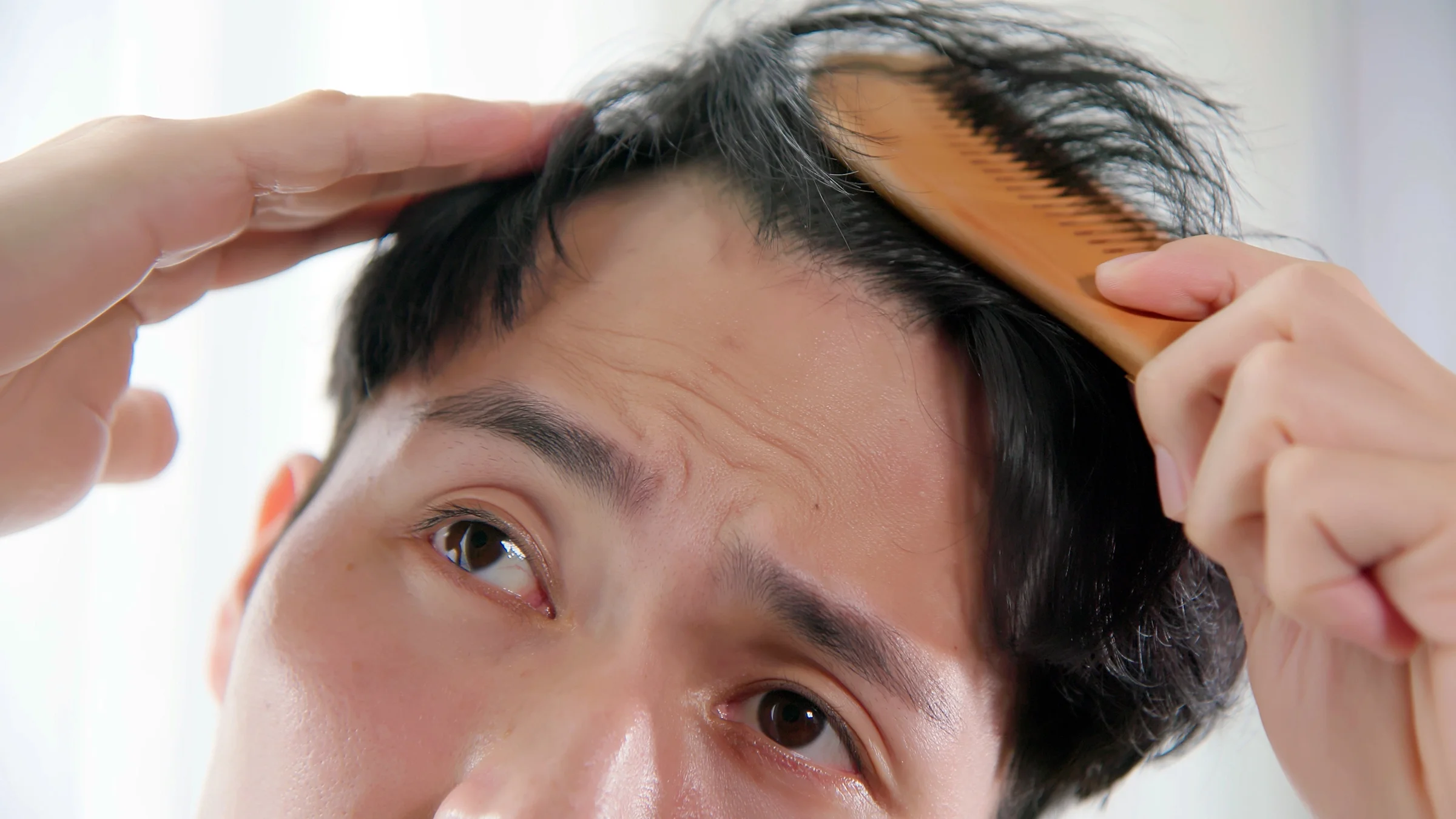 A man studies his hairline. 