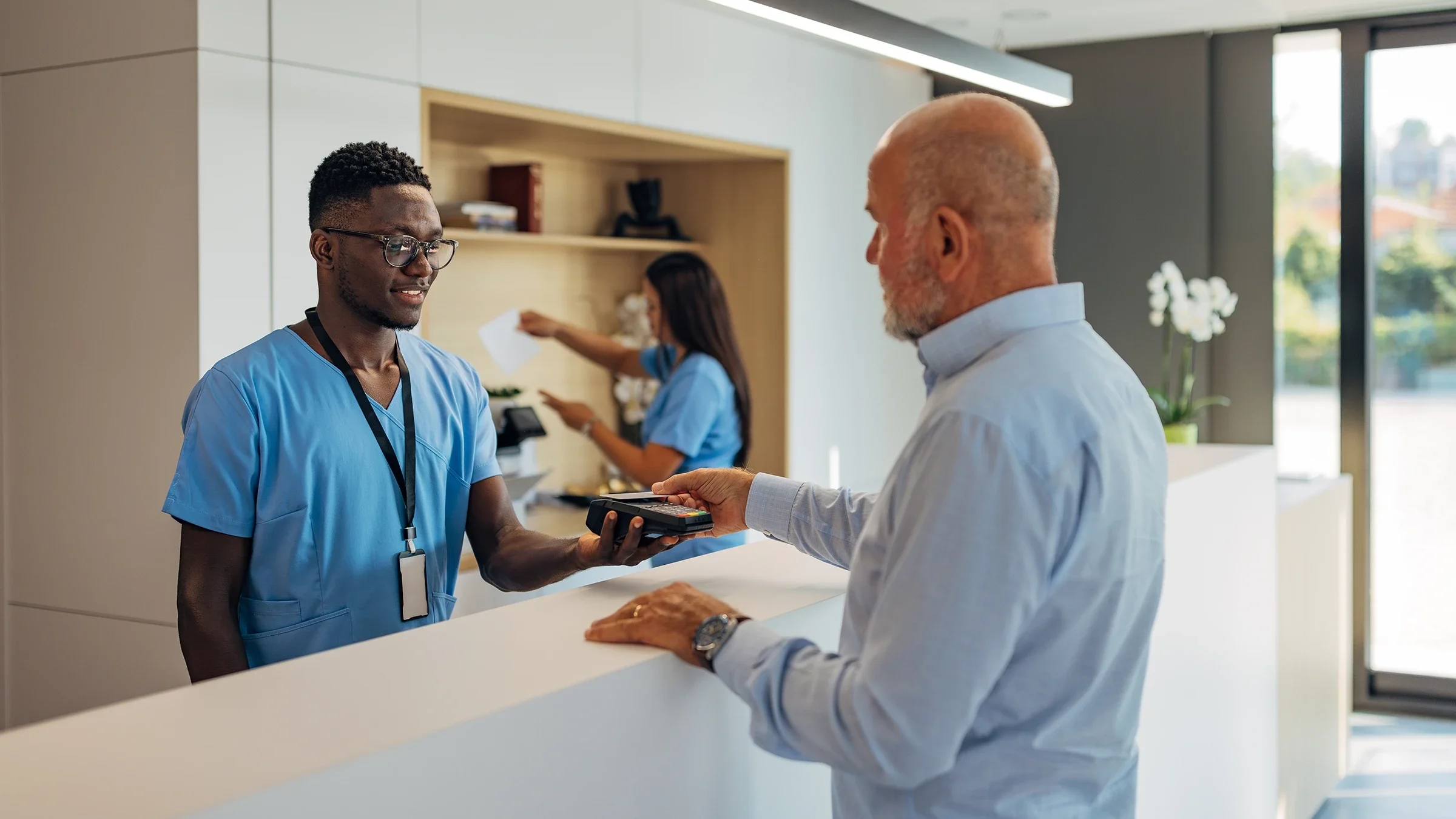 A customer taps his card to pay for medical services.