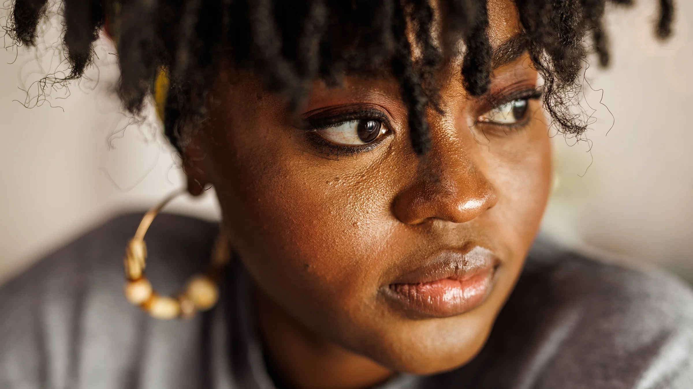 A woman looks away while contemplating something.