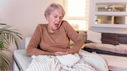 An older adult experiencing abdominal pain on their couch.
stefanamer/iStock via Getty Images Plus