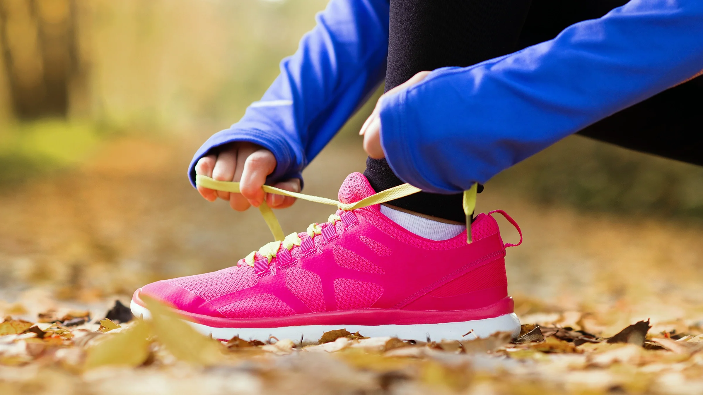 A close-up of a woman tying a sneaker