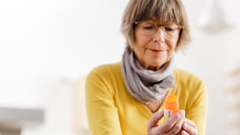 shingles: medication: prescription: older woman looking at prescription bottle-174794956