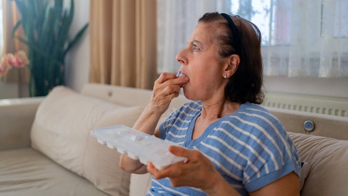 A woman chews on an ice cube.