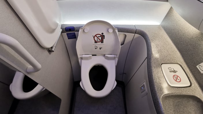 There is an airplane toilet in a small room.
